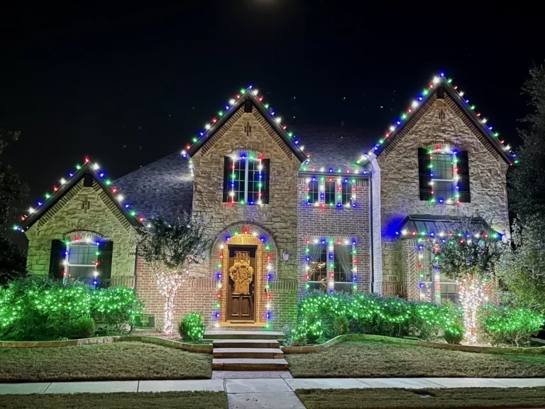 Stone home with Christmas lights and lighted shrubs