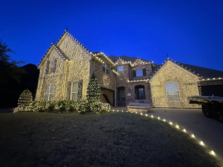 Stone home with warm white roofline Christmas lights at dusk