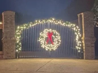 Iron gate with a lighted Christmas wreath and garland