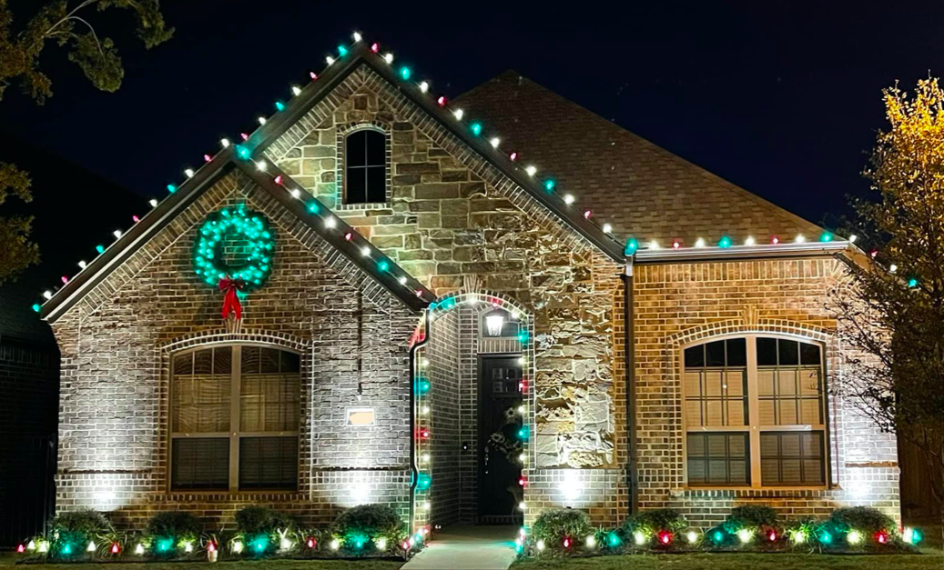 Brick home lit with a red, white and green C9 Christmas light pattern and a lit wreath